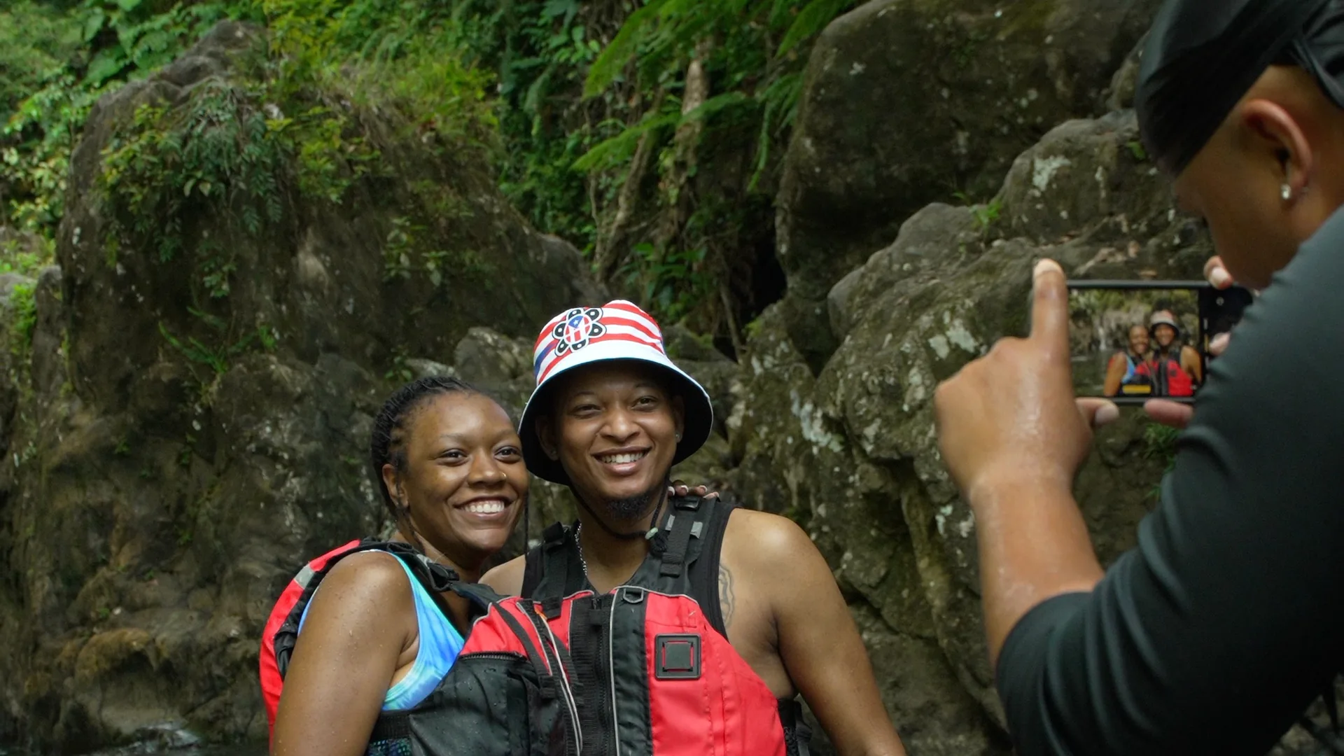 Two guests smiling in life vests while their guide photographs them on an El Yunque rainforest tour in Puerto Rico