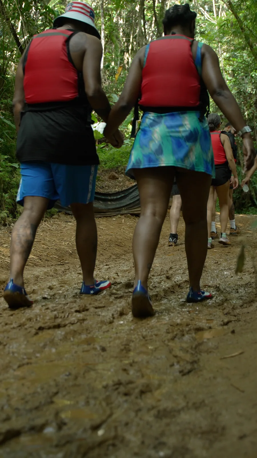 Small group hiking a muddy jungle trail on a guided El Yunque rainforest tour in Puerto Rico