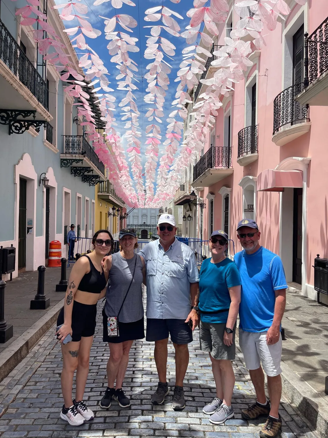Tour group on Calle Fortaleza in Old San Juan beneath the hanging art installation, with La Fortaleza at the end of the street