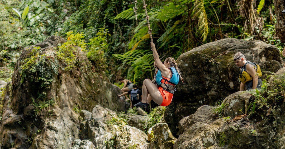 Visitor on a rope swing in the dense rainforest of El Yunque National Forest, Puerto Rico